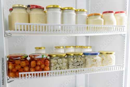 Swiss cheese in the form of small balls sprinkled with red pepper. cheese balls belper knoll. Feta cheese with spicy herbs. Cheeses in glass jars in the refrigerator. Soft cream cheeses in jars photo