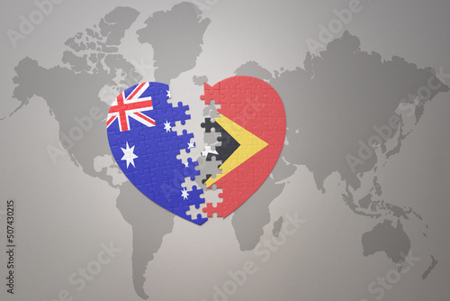 puzzle heart with the national flag of east timor and australia on a world map background. Concept.