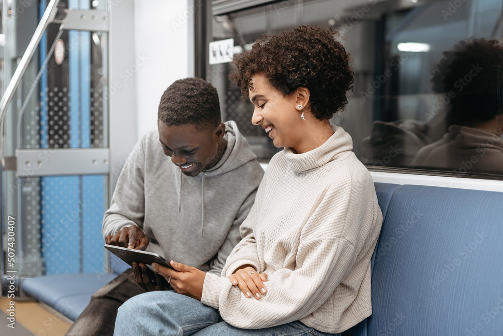young couple using a digital tablet while sitting in a subway car.