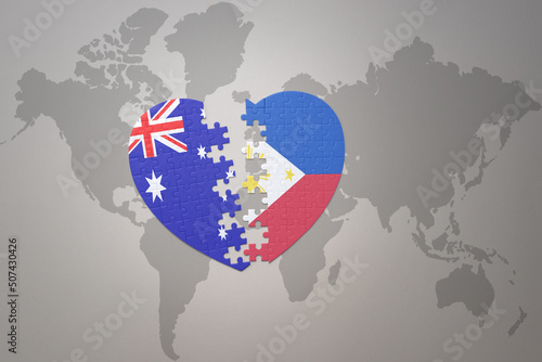 puzzle heart with the national flag of philippines and australia on a world map background. Concept.