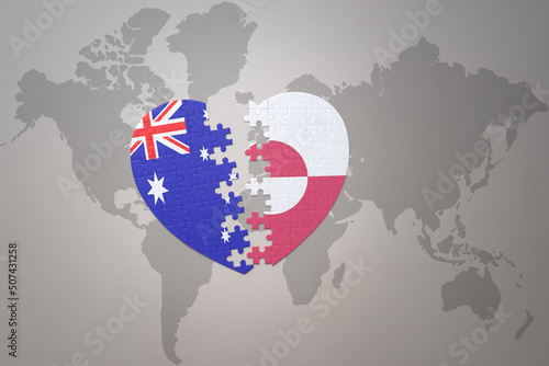 puzzle heart with the national flag of greenland and australia on a world map background. Concept.