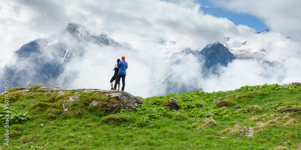 Panoramabild zwei Wanderer schauen in die nebelverhangenen Alpen