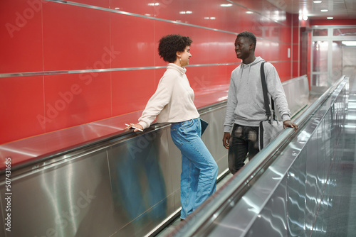 couple of students are talking standing on the escalator in the
