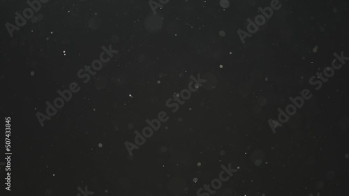 Slow motion real dust particles floating in the air with natural sunlight over black background
