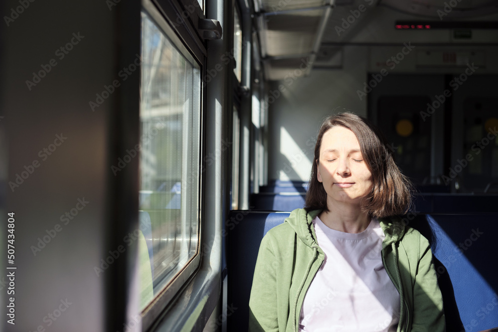 Peaceful caucasian woman with closed eyes enjoying being alone in the train. Mental health concept. Beautiful shadows from sunlight. Peaceful caucasian woman with closed eyes enjoying being alone in the train. Mental health concept. Beautiful shadows from sunlight.