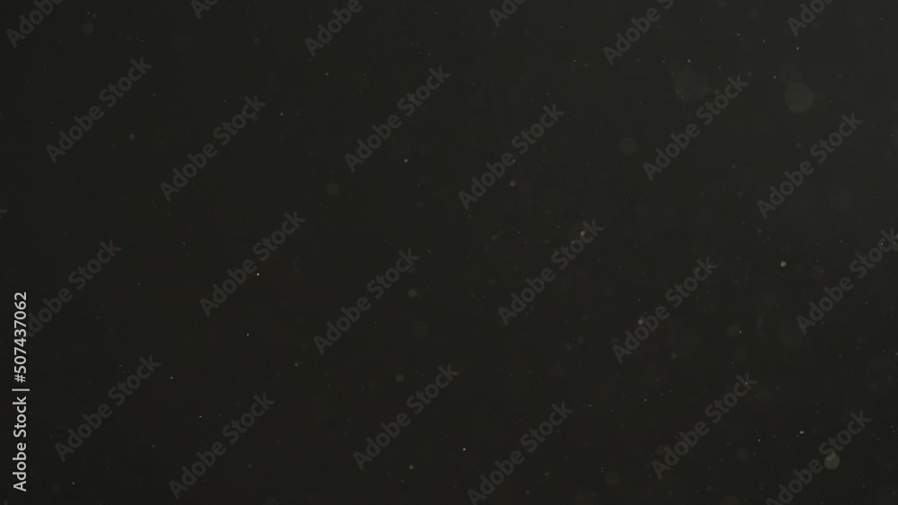 Slow motion real dust particles floating in the air with natural sunlight over black background Slow motion real dust particles floating in the air with natural sunlight over black background