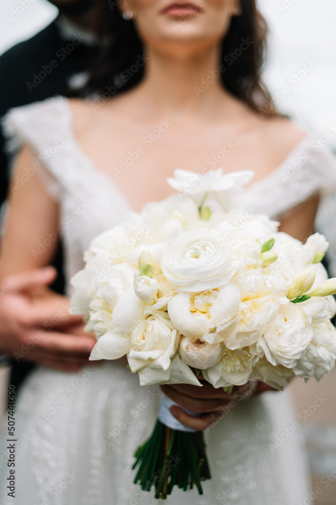 bride in a white dress with a chic bouquet in her hands. Luxury wedding bouquet. The girl is holding flowers - roses, peonies, archedes.
