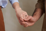 Close-up studio shot of unrecognizable affianced man and woman tenderly holding their hands