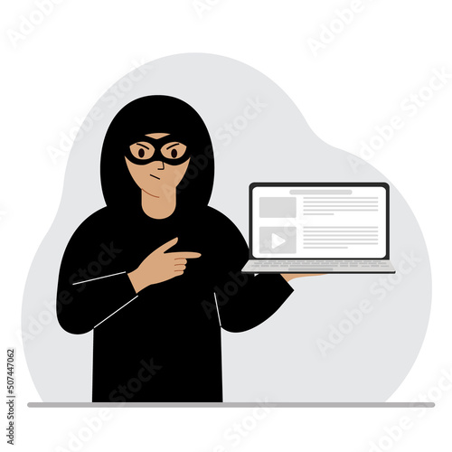 Hacker in a black mask with a computer. The cybercriminal is holding a laptop. Cyber attack, mobile phishing, scam.