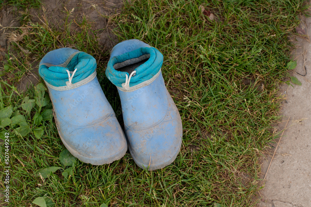 dirty blue rubber boots on the green grass dirty blue rubber boots on the green grass