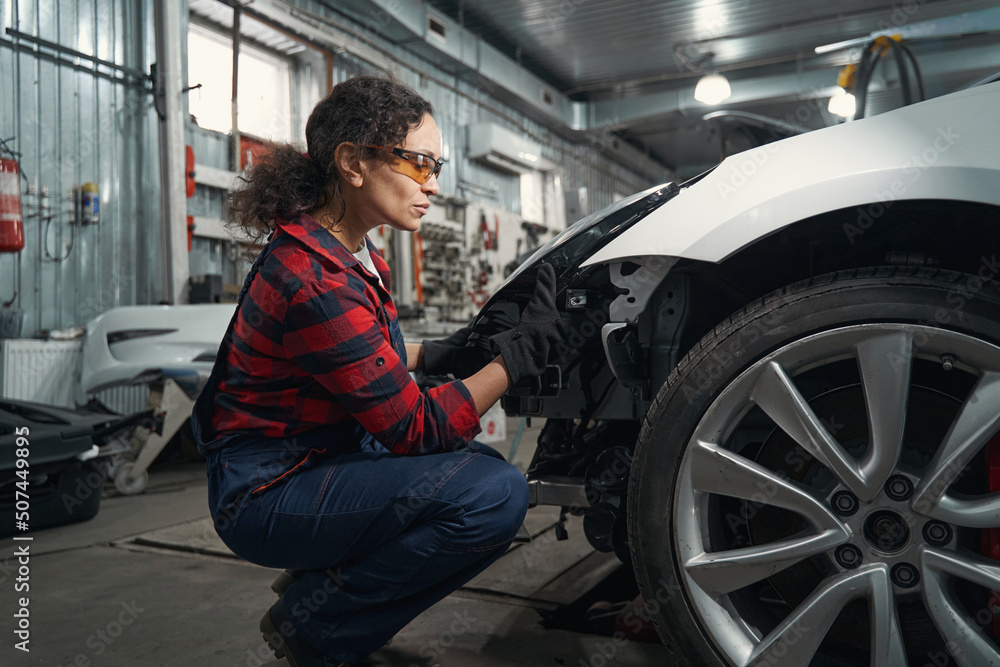 Woman car mechanic repairing vehicle in garage Woman car mechanic repairing vehicle in garage