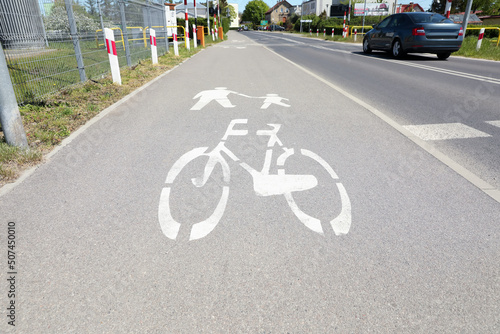 Bicycle lane with white sign painted on asphalt near road