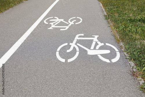 Bicycle lane with white sign painted on asphalt near sidewalk