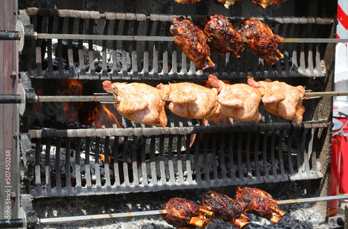 rotisserie with spit-roasted chickens and pork shank and ham meat while cooking in the restaurant of the village festival