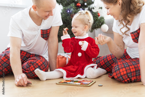 Toddler child with cochlear implant plays with parents under christmas tree - deafness and innovating medical technologies for hearing aid and diversity
