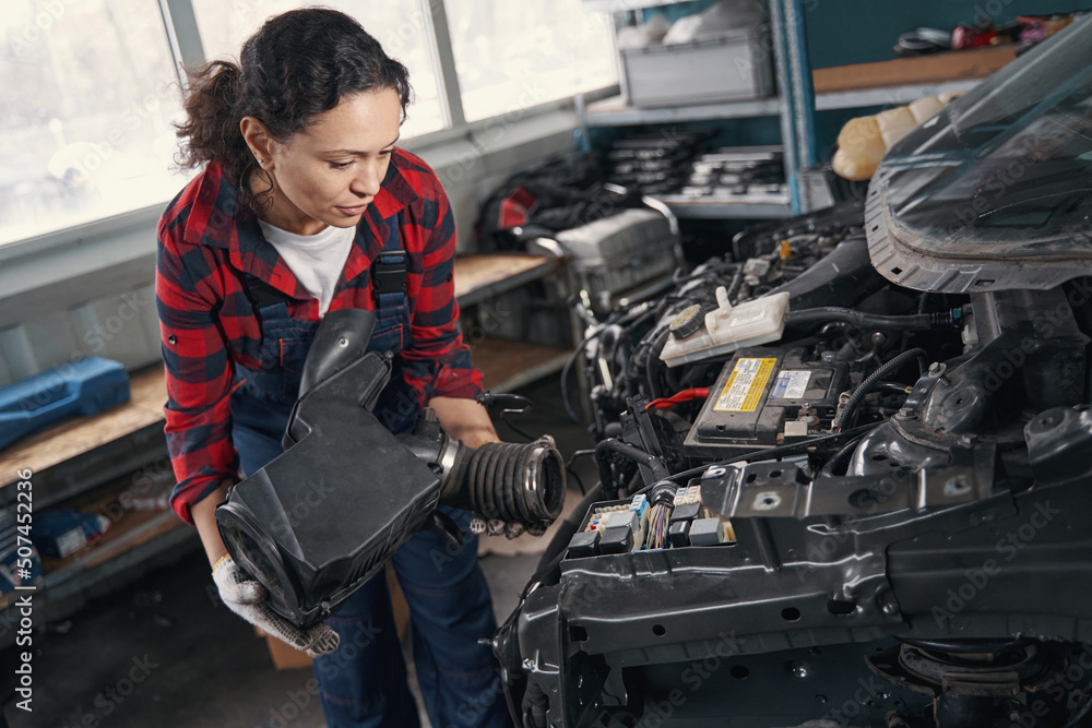Woman automobile mechanic repairing car engine in auto repair shop Woman automobile mechanic repairing car engine in auto repair shop