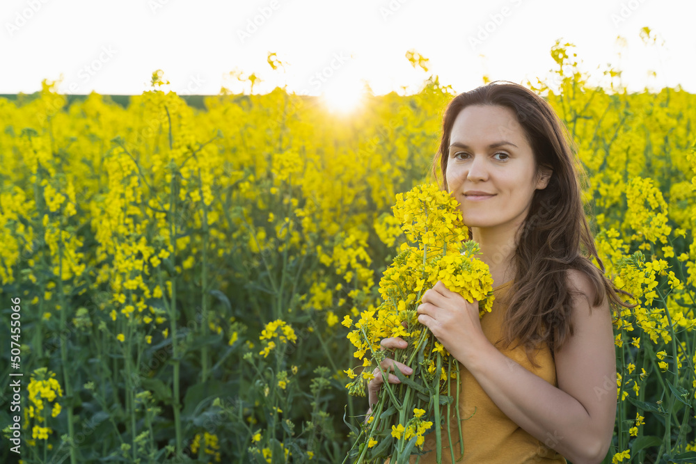 A girl in yellow. Woman with a bouquet of rapeseed flowers in the field A girl in yellow. Woman with a bouquet of rapeseed flowers in the field