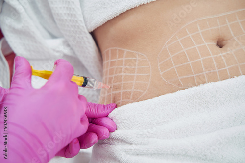 Dermatologist performing non invasive fat reduction procedure in beauty center photo