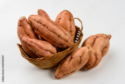 Sweet carrot potatoes in a basket isolated on white background.
