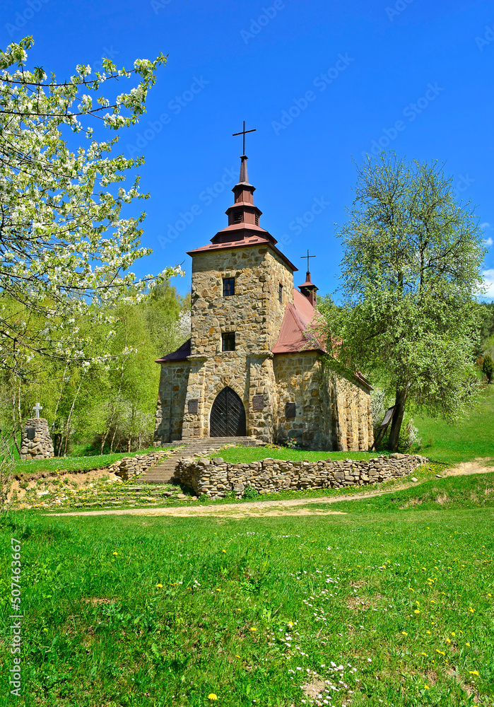 A  stone church in the picturesque landscape in Huta Polanska of the Low Beskids (Beskid Niski) in spring sunny day, Poland