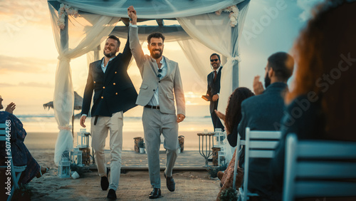 Handsome Gay Couple Exchange Rings and Kiss at a Beach Wedding Ceremony Venue at Sunset. Two Happy Men in Love Share Their Big Day with Diverse Multiethnic Friends. LGBTQ Relationship Goals.