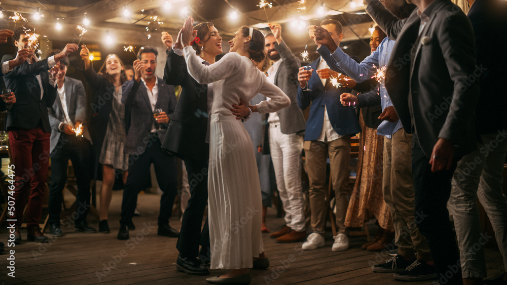Beautiful Happy Lesbian Couple Celebrate Wedding at an Evening Reception Party with Diverse Multiethnic Friends. Queer Newlyweds Dancing at a Restaurant Venue. LGBTQ Relationship and Family Goals.