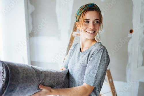 Quadro em tela Young woman renovating her bedroom and has a painter carpet in her hand and look