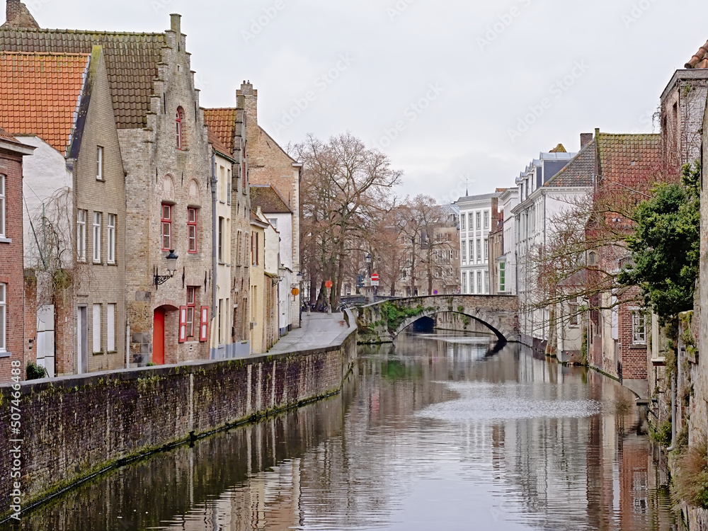 Canal with medieval houses and arch bridge in the city of Bruges