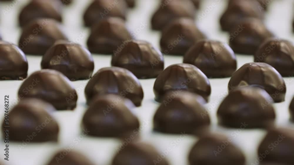A view of a lot of chocolates without wrappers on a moving conveyor belt. Close-up shooting. A view of a lot of chocolates without wrappers on a moving conveyor belt. Close-up shooting.