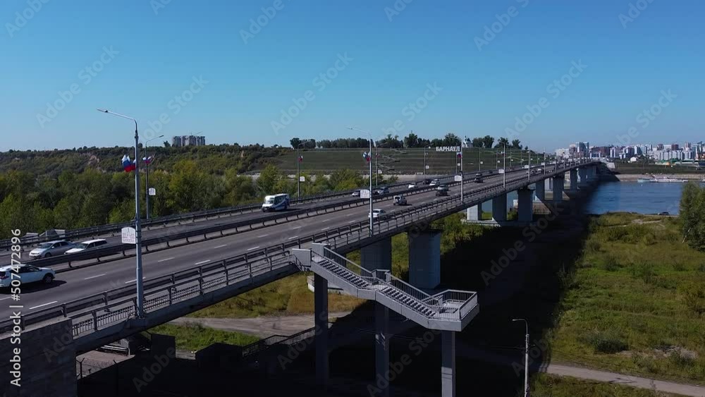 Daytime traffic on a multi-lane road at the entrance to the city via the bridge, drone view of traffic Daytime traffic on a multi-lane road at the entrance to the city via the bridge, drone view of traffic