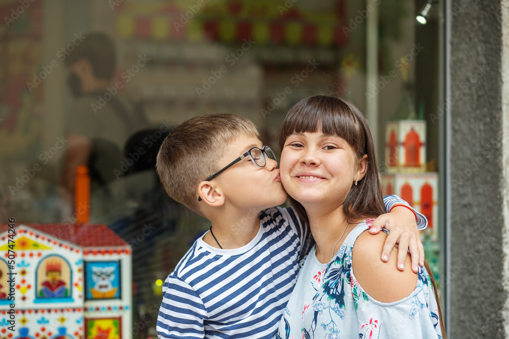 Obraz premium Little brother hugs and kisses his older sister. Happy family. Have fun spending time together.