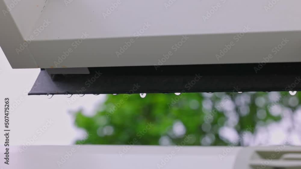 Close up view of falling raindrops from  window frame of skylight during rain.
