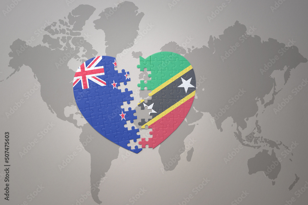 Obraz premium puzzle heart with the national flag of new zealand and saint kitts and nevis on a world map background. Concept.