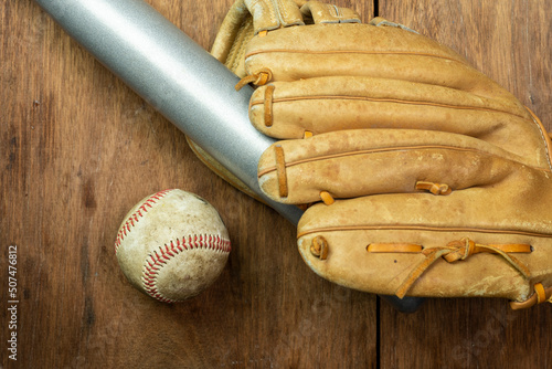 Vintage classic leather baseball glove and baseball bat isolated on wooden background.