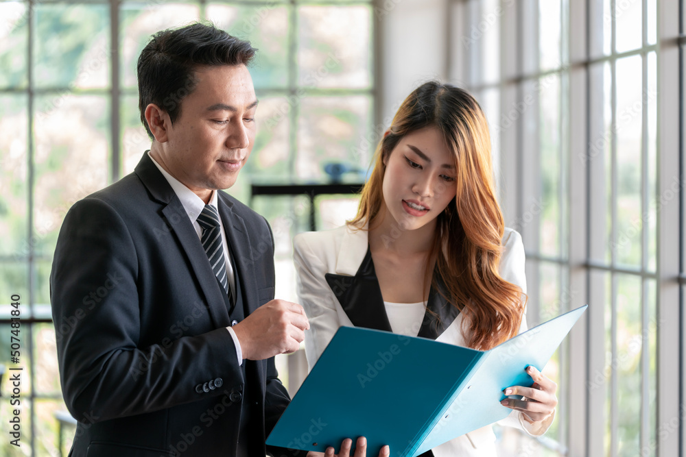 Asian business executive checking the work of a female employee in her job file. Talk with a smiling face and have fun and relax. at the company office Asian business executive checking the work of a female employee in her job file. Talk with a smiling face and have fun and relax. at the company office