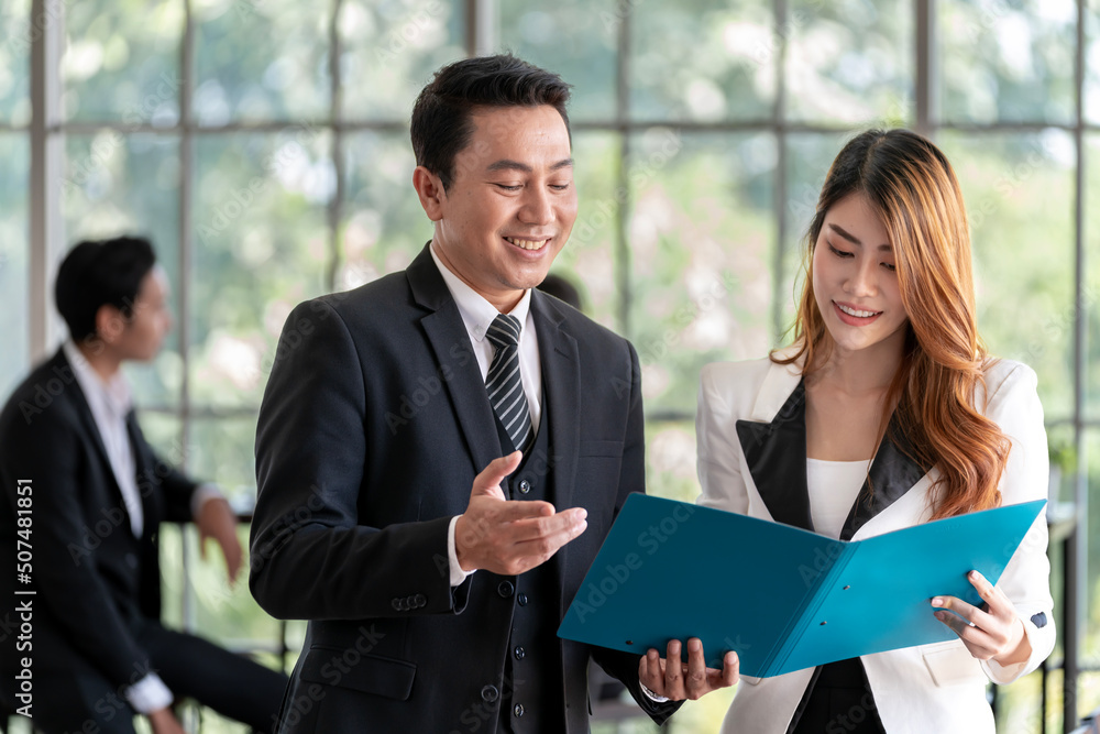 Asian business executive checking the work of a female employee in her job file. Talk with a smiling face and have fun and relax. at the company office