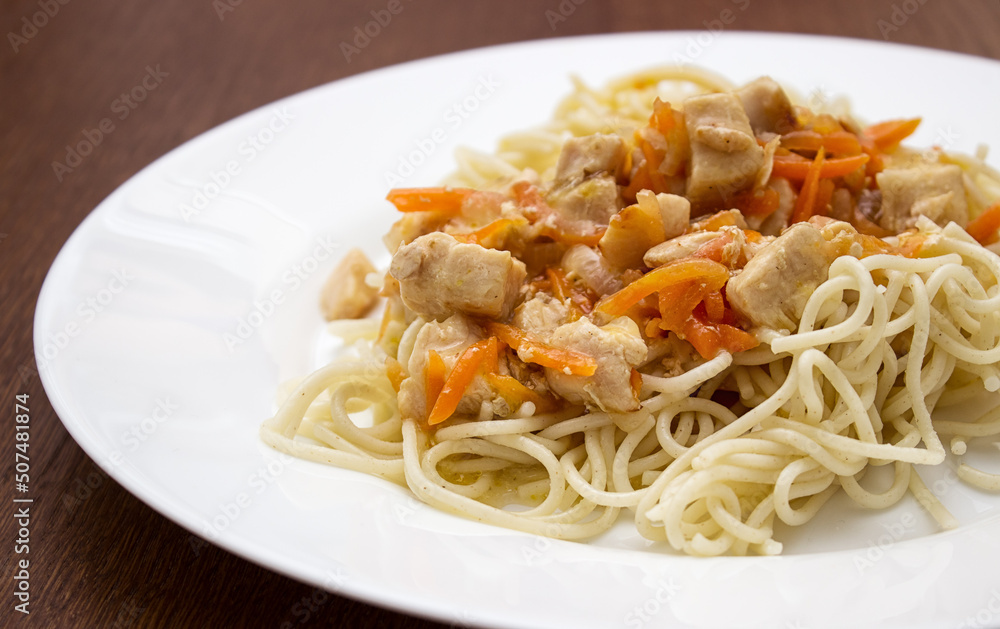 spaghetti with meat and vegetables on a white plate