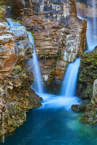 Detail of two waterfalls pouring into a river through rocky cliffs