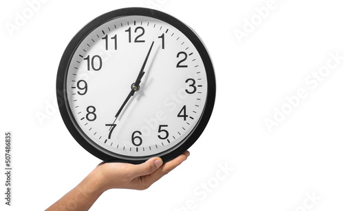 Hand holds a large black clock on a white background.