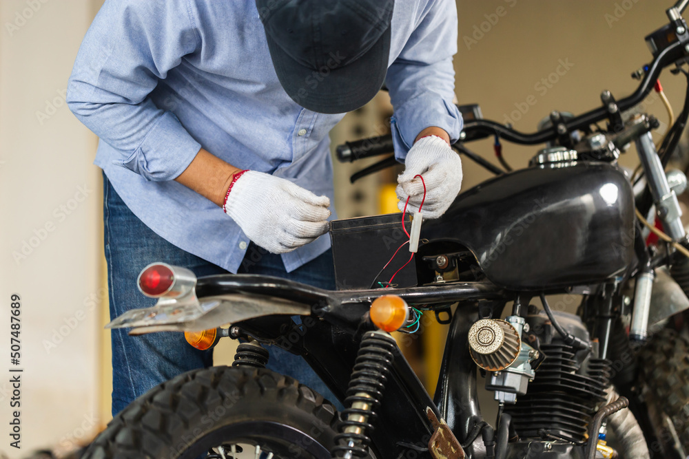 Man repairing motorcycle in repair shop, Mechanic fixing motorbike in workshop garage, Repairing and maintenance concepts Man repairing motorcycle in repair shop, Mechanic fixing motorbike in workshop garage, Repairing and maintenance concepts