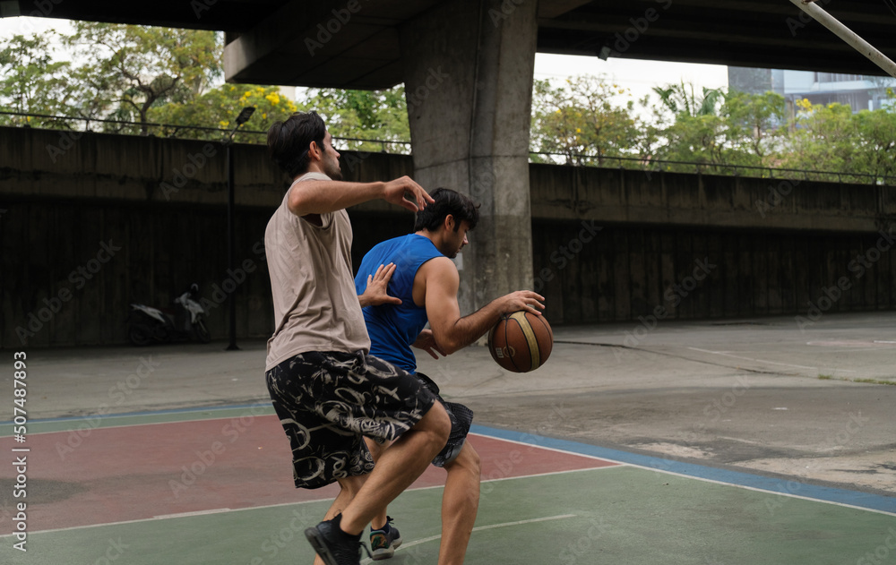 Two caucasian men pratice baskegball in court at urban street. Two caucasian men pratice baskegball in court at urban street.