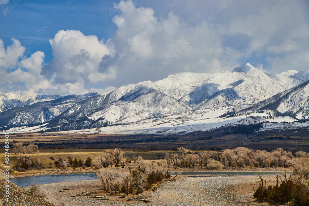 Beautiful white snowy mountains with spring fields and river in foreground