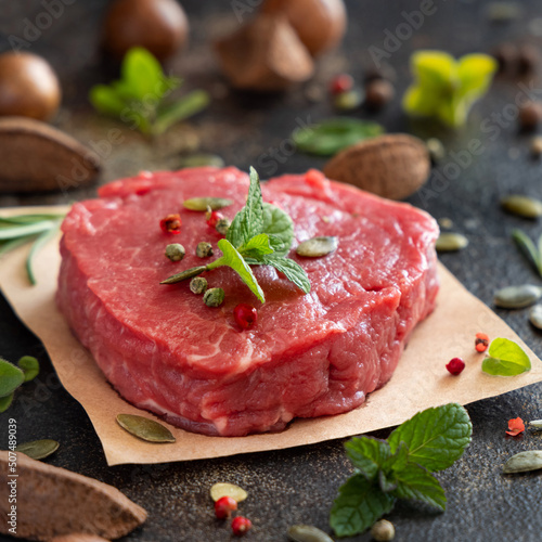 Raw beef fillet steak with herbs and spices on dark table close up