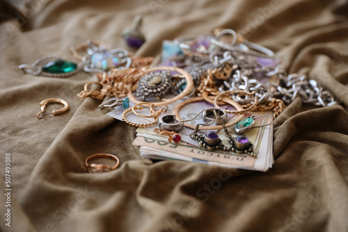 Fotografia Bunch of stolen jewelry and money on military uniform cloth fabric