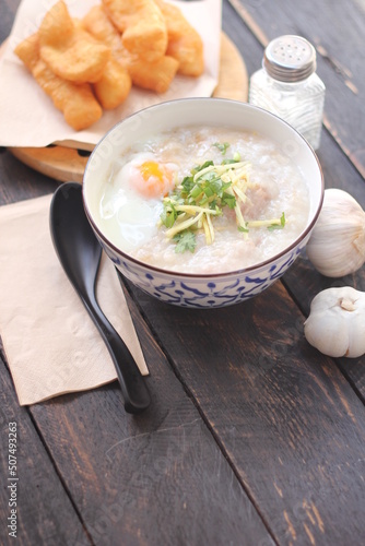 Congee in a Thai-patterned cup and fried batter served in an Asian-style cup on a black table with fried batter that we call 