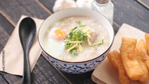 Joke or Congee in a Thai style cup Served on a black wooden table. It's an Asian breakfast.