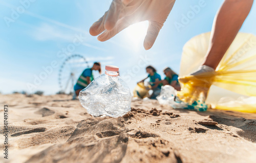 Carta da parati Group of eco volunteers picking up plastic trash on the beach - Activist people