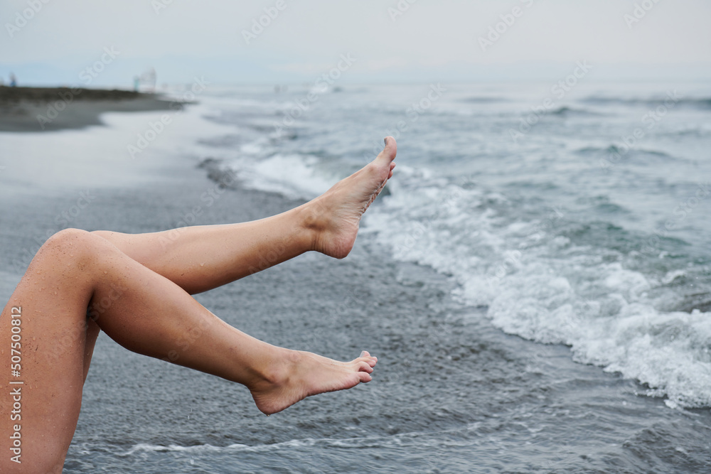 in the air women's legs against the background of the sea wave in the air women's legs against the background of the sea wave