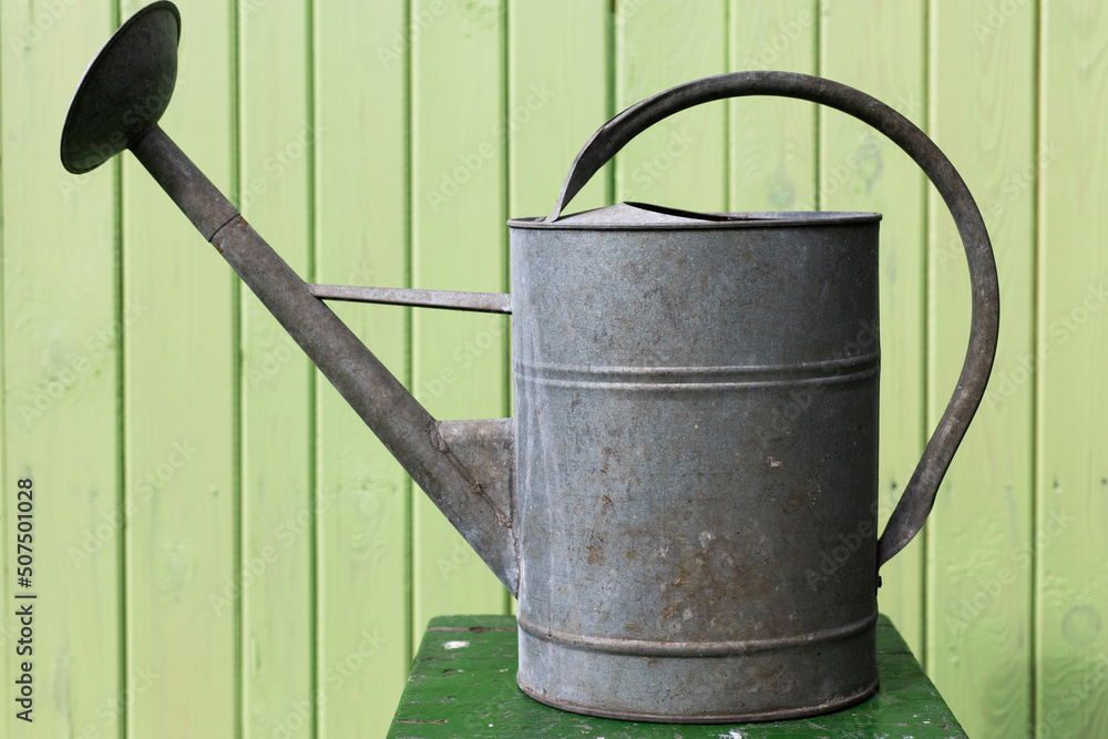 watering can on the background of a wooden wall watering can on the background of a wooden wall