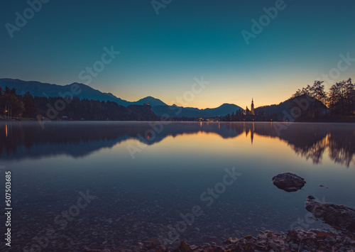 Lake Bled at Sunrise. Church  castle and the mountains are basking in the morning sun